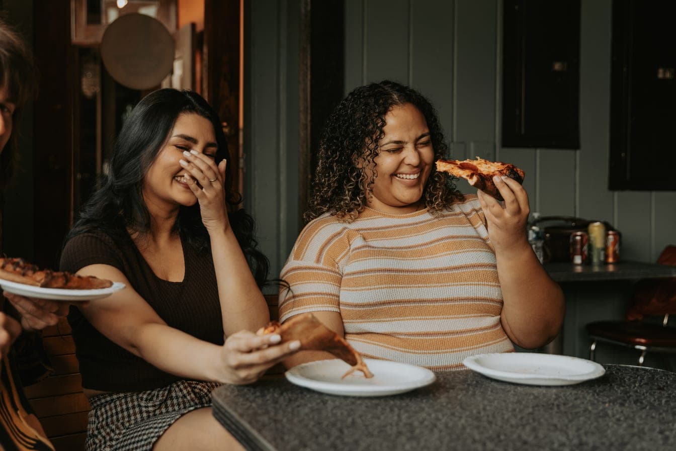 Two flatmates laughing together over food at home